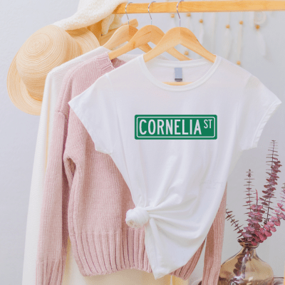 White t-shirt with green street sign that says Corenlia St